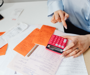A woman types numbers into a calculator.  She is surrounded by different receipts.