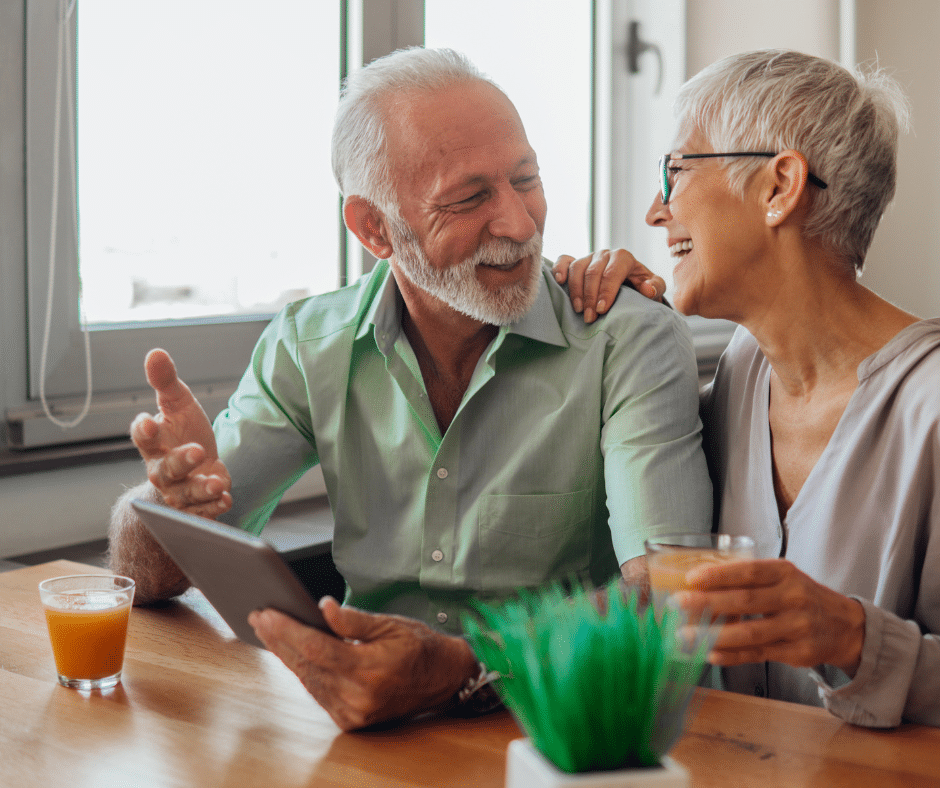 A couple in their 60s look at one another happily.  They have a notebook of information in front of them